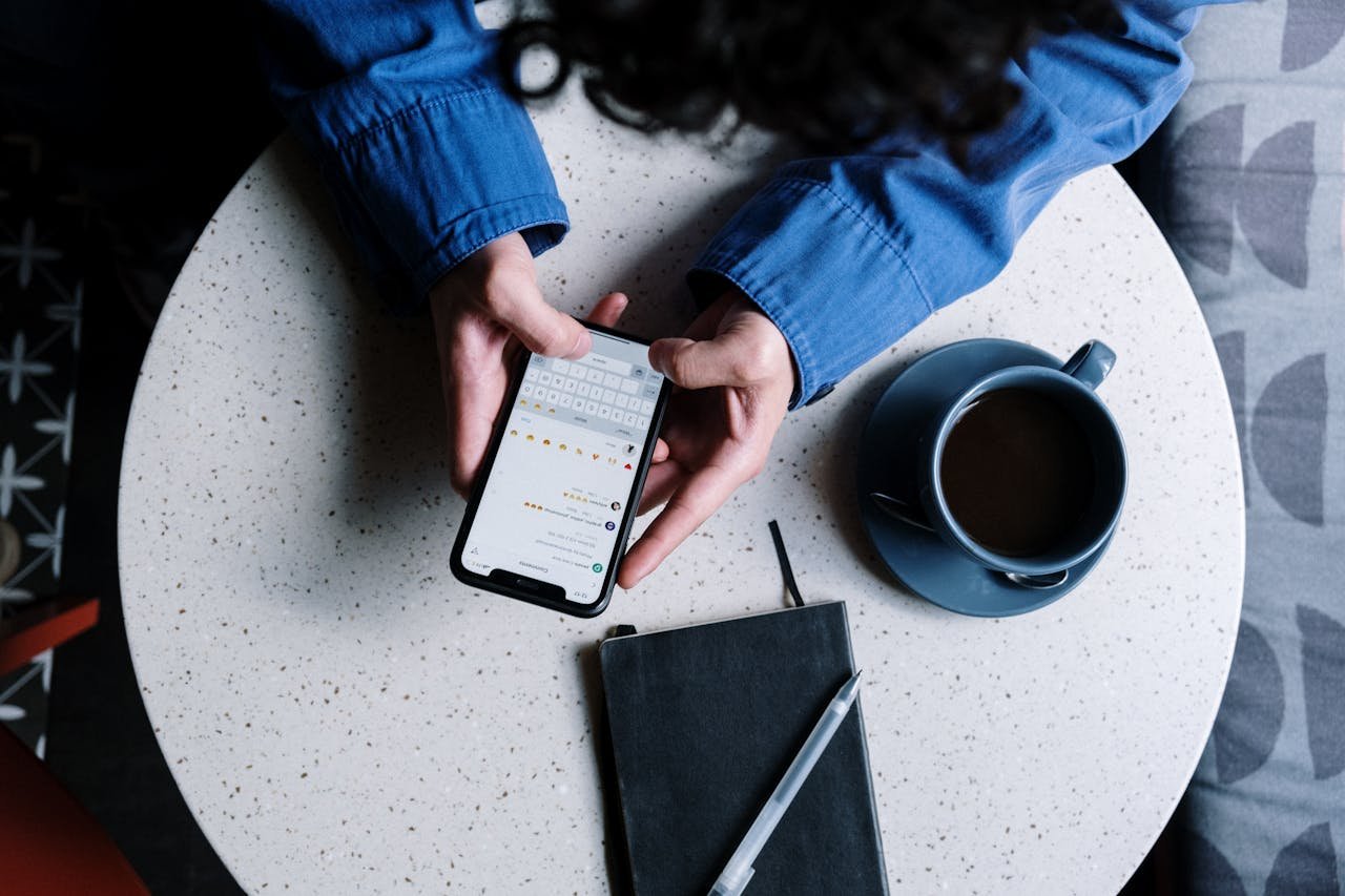 Crafting Captivating Headlines: Your awesome post title goes here Person using smartphone at table with notebook and coffee, ideal for tech and lifestyle themes.