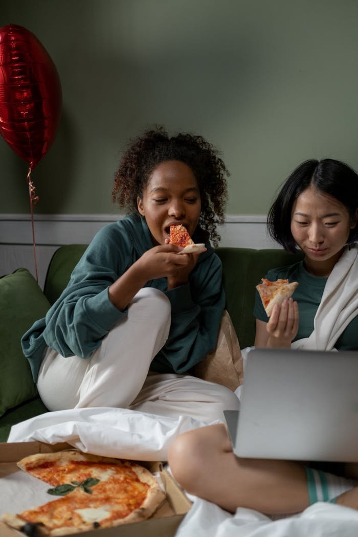 Mastering the First Impression: Your intriguing post title goes here Two friends enjoying pizza and watching a movie together on a couch, creating a cozy atmosphere.